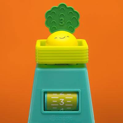 veggie stacker toy with yellow veggie piece on an orange background. 