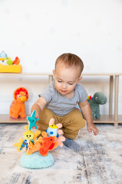 A little boy holds a little plush starfish, which will connect to the magnet on the plush coral base.